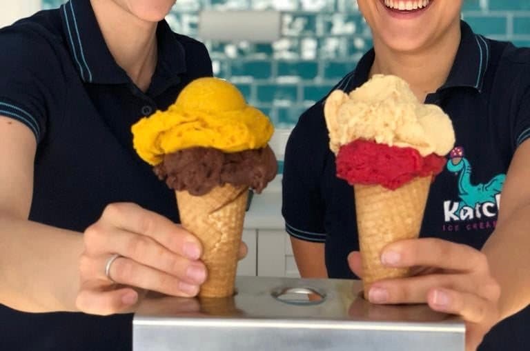 Zwei Eiswaffeln mit Mango- und Erdbeereis, gehalten von Katchi-Mitarbeitern