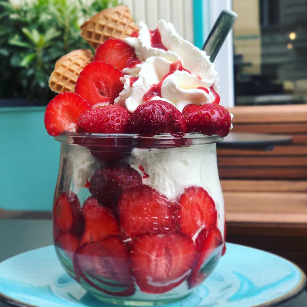 Erdbeerbecher mit frischen Erdbeeren, Sahne und Mini-Waffeln