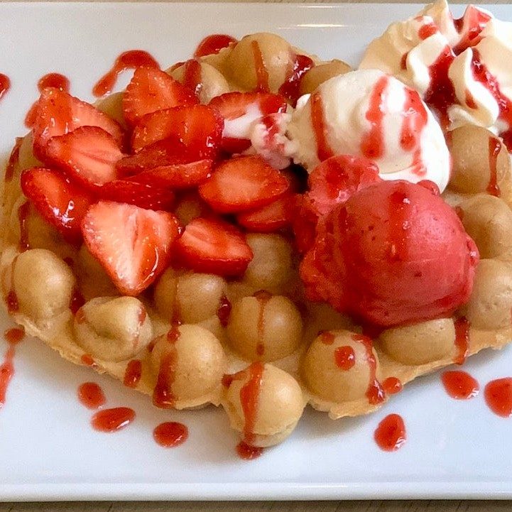 Bubble Waffle mit Erdbeeren, Sahne und Eis auf dem Teller