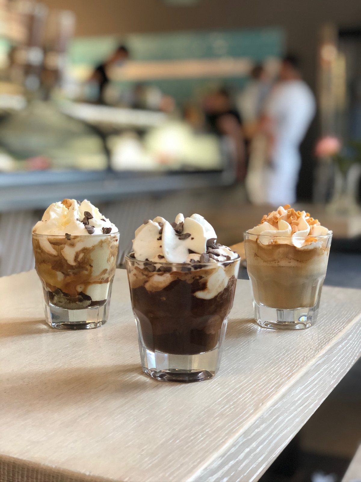Drei kleine Eisbecher im Glas mit Schokolade, Sahne und Karamell in der Katchi-Eisdiele