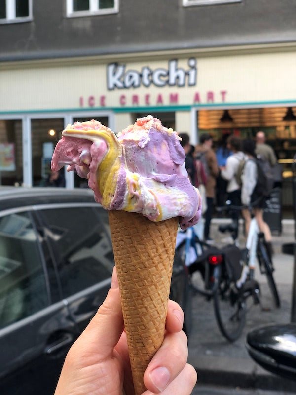 Eis in Lila und Gelb in der Waffel vor einer Katchi-Eisdiele