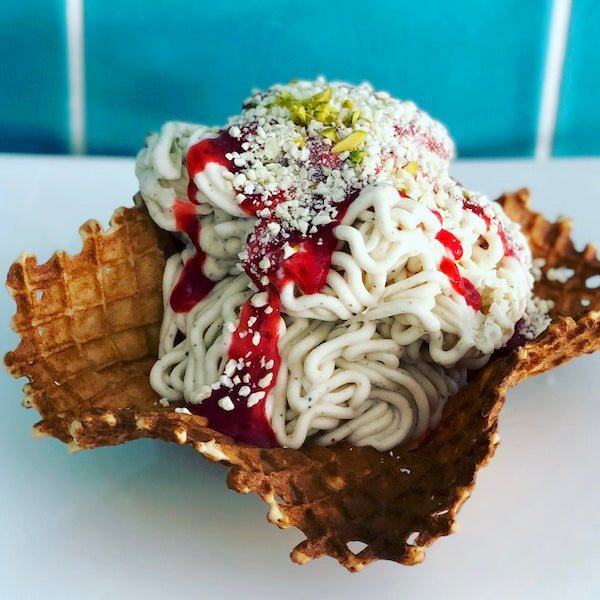 Spaghettieis im hausgemachten Katchi Waffel-Körbchen, getoppt mit Erdbeersoße und Pistazienstreuseln