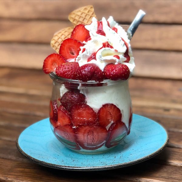 Erdbeerbecher im Glas mit frischen Erdbeeren, Sahne und Waffel